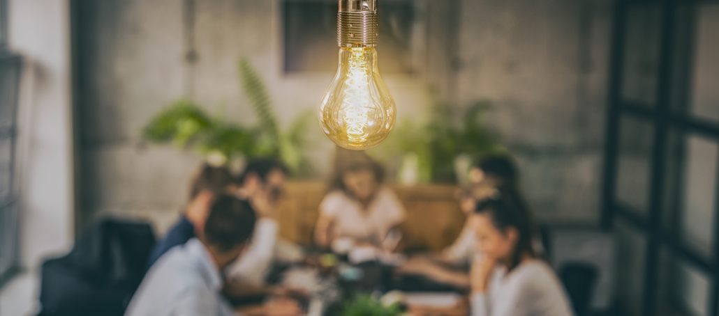 Team brainstorming at table under lightbulb