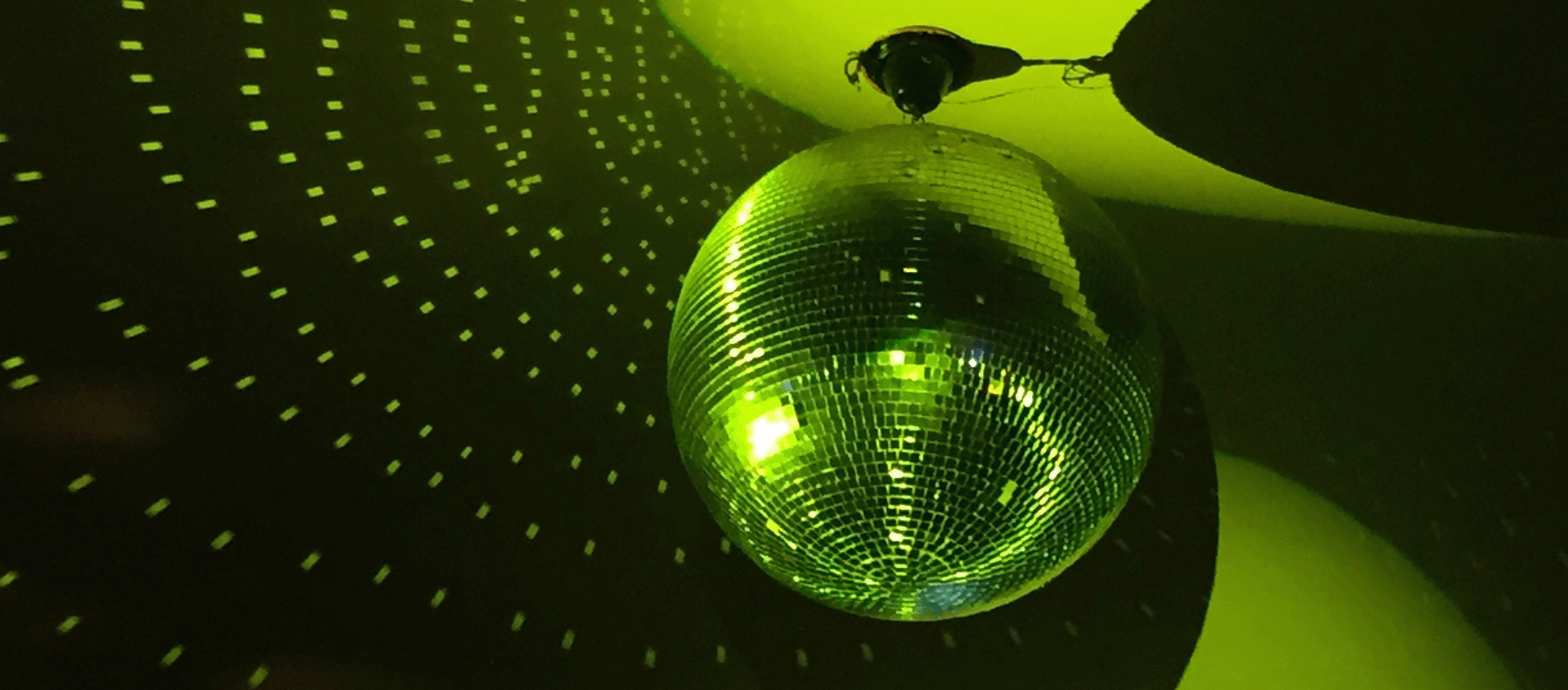 Disco ball reflecting green light in dark room