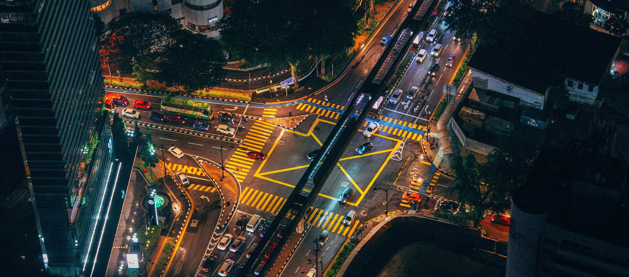 Arial view of heavy traffic coming to a 4 way intersection at night.